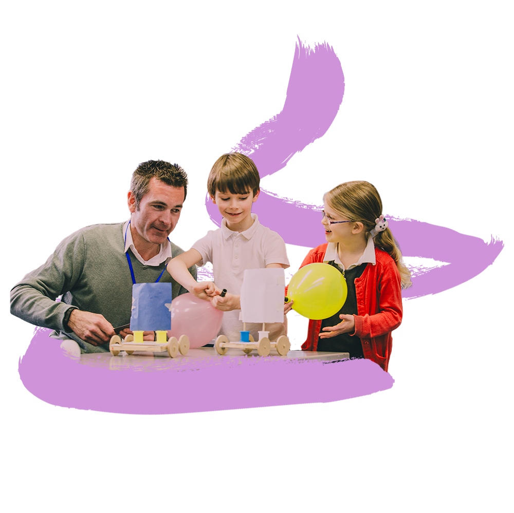A teacher sits with two children in a classroom